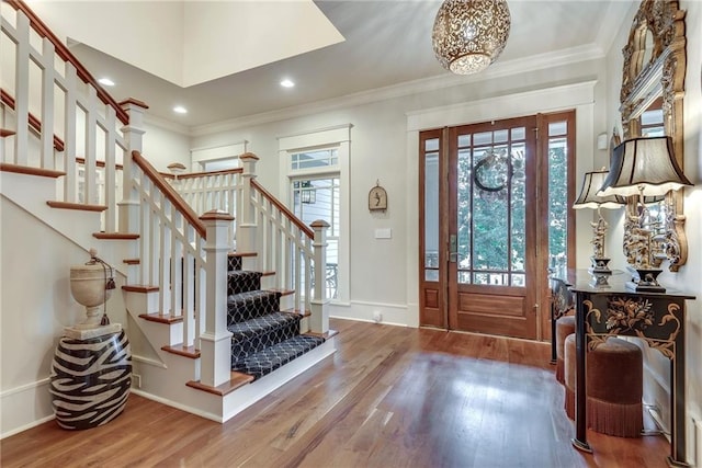 entrance foyer with crown molding, hardwood / wood-style floors, and a chandelier