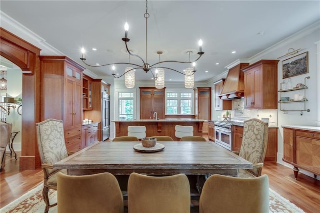 dining area with crown molding, light hardwood / wood-style floors, sink, and a notable chandelier