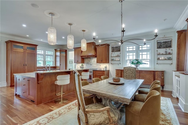 dining space featuring crown molding, sink, light hardwood / wood-style flooring, and a notable chandelier