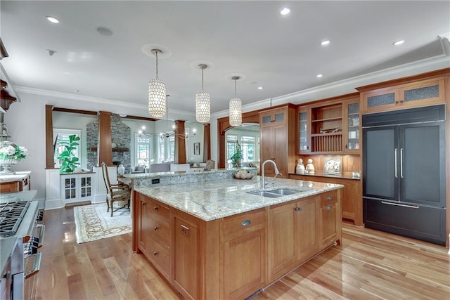 kitchen with pendant lighting, light hardwood / wood-style floors, sink, an island with sink, and ornamental molding