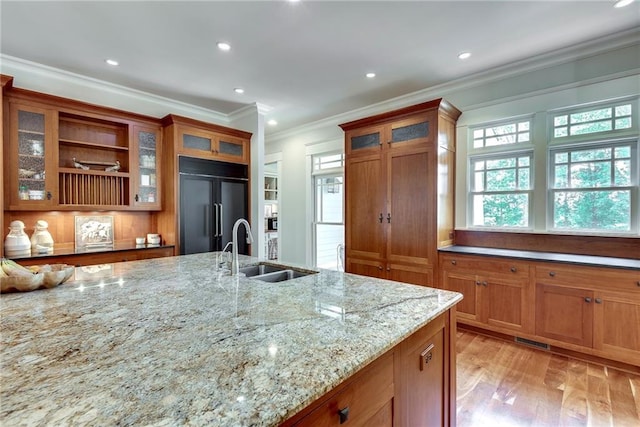 kitchen featuring ornamental molding, sink, light hardwood / wood-style flooring, paneled built in fridge, and light stone countertops