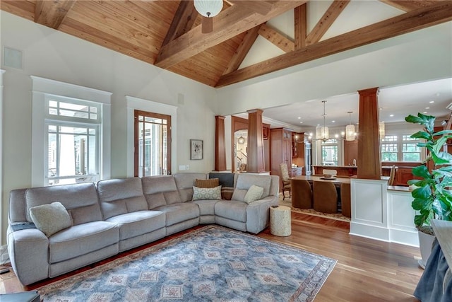 living room with light wood-type flooring, plenty of natural light, ornate columns, and high vaulted ceiling