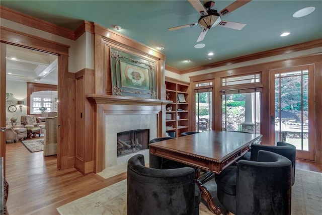 dining area featuring light wood-type flooring, ornamental molding, ceiling fan, and a premium fireplace