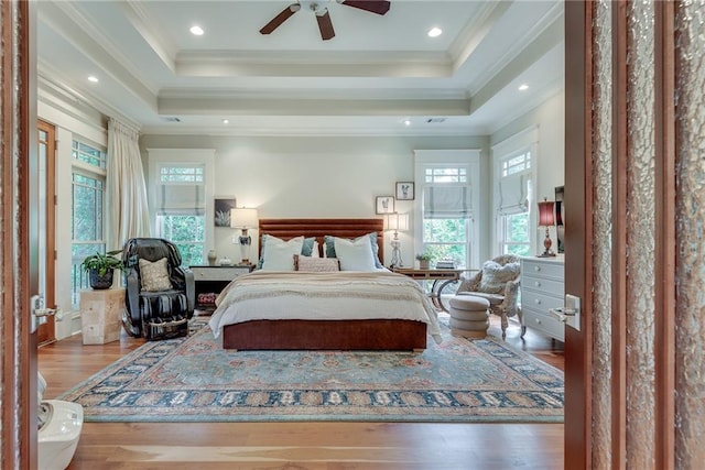 bedroom with ceiling fan, ornamental molding, a raised ceiling, and hardwood / wood-style floors