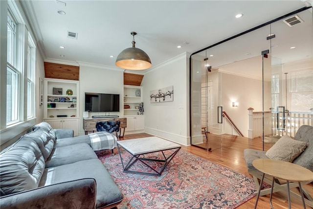 living room featuring built in shelves, light hardwood / wood-style flooring, and ornamental molding