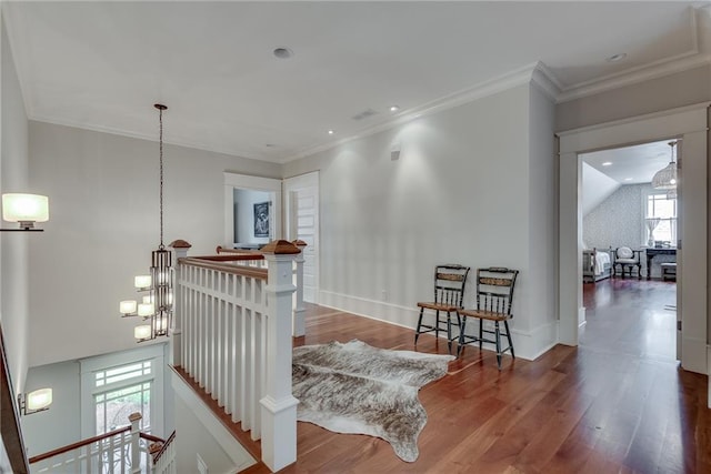 hallway featuring wood-type flooring, an inviting chandelier, and crown molding