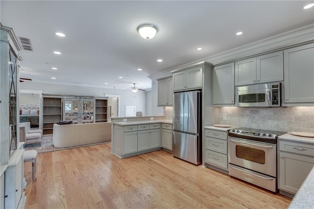 kitchen with ceiling fan, tasteful backsplash, gray cabinetry, stainless steel appliances, and light wood-type flooring