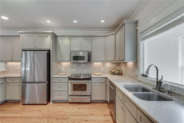 kitchen with light hardwood / wood-style floors, sink, decorative backsplash, appliances with stainless steel finishes, and crown molding