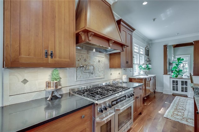 kitchen with decorative backsplash, wood-type flooring, custom exhaust hood, ornamental molding, and stainless steel range