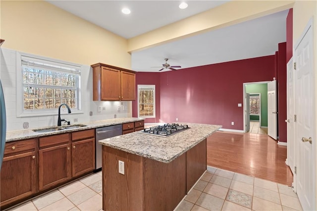 kitchen with appliances with stainless steel finishes, light tile patterned floors, a kitchen island, and sink