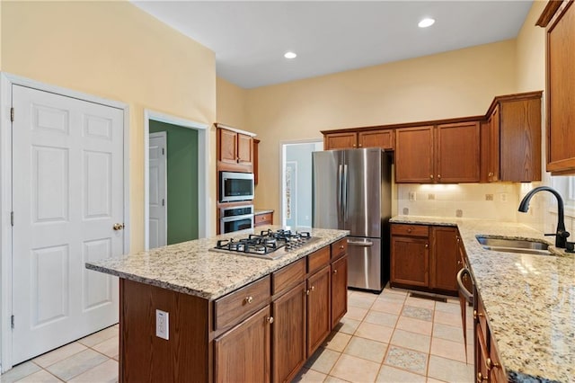 kitchen featuring light stone countertops, sink, light tile patterned floors, a kitchen island, and appliances with stainless steel finishes