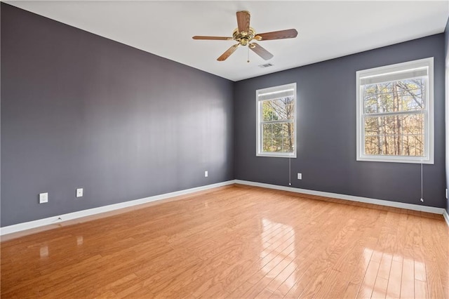 spare room featuring ceiling fan, light hardwood / wood-style floors, and a wealth of natural light