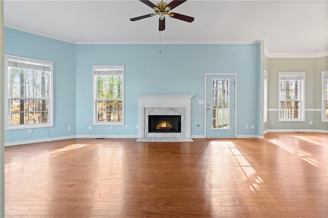 unfurnished living room featuring ceiling fan, light wood-type flooring, a premium fireplace, and ornamental molding