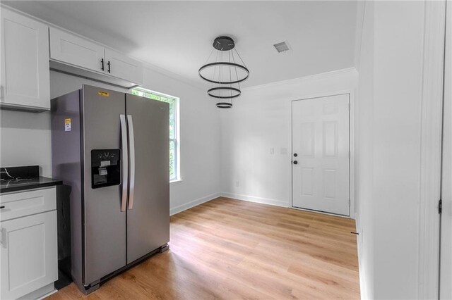 1111 Osborne St SW, Atlanta, GA 30310 - kitchen with dark countertops, light wood-style floors, crown molding, stainless steel refrigerator with ice dispenser, and white cabinetry