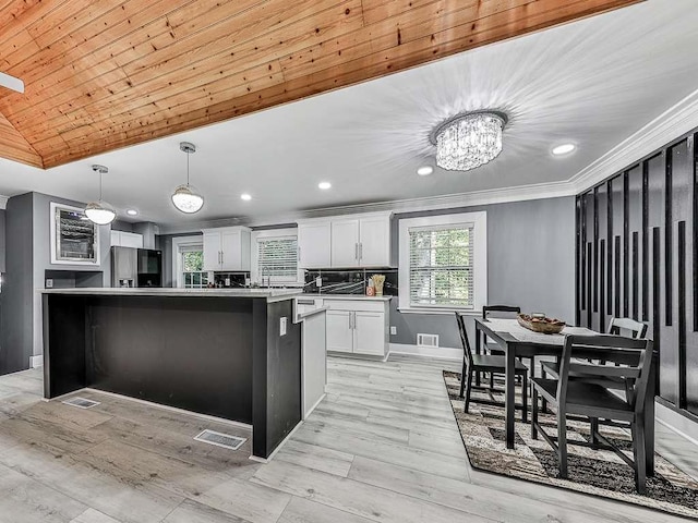 kitchen featuring black fridge, pendant lighting, white cabinets, light hardwood / wood-style floors, and a kitchen island