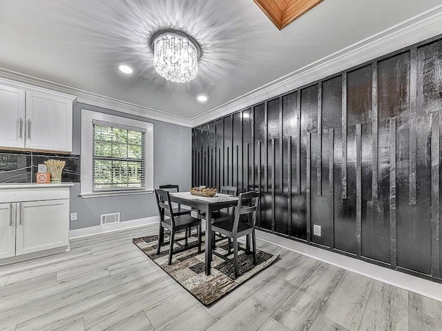 dining area featuring crown molding, light hardwood / wood-style flooring, and a notable chandelier