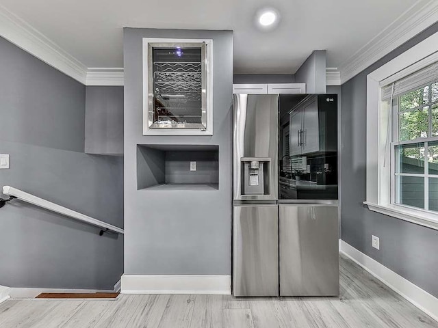 kitchen with stainless steel fridge, light hardwood / wood-style floors, and ornamental molding