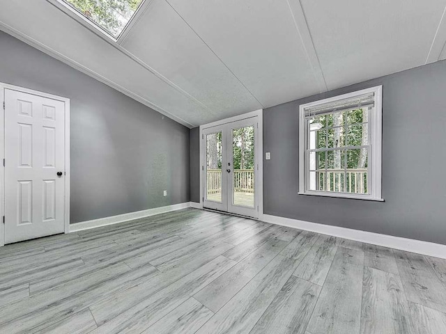 empty room with lofted ceiling, light hardwood / wood-style flooring, and french doors