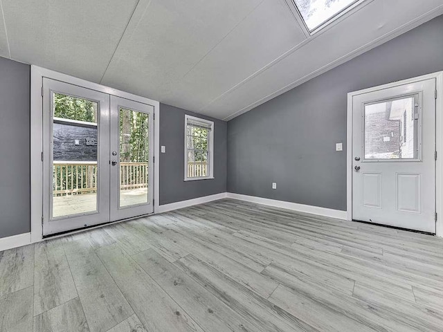 interior space with a textured ceiling, light hardwood / wood-style flooring, vaulted ceiling, and plenty of natural light