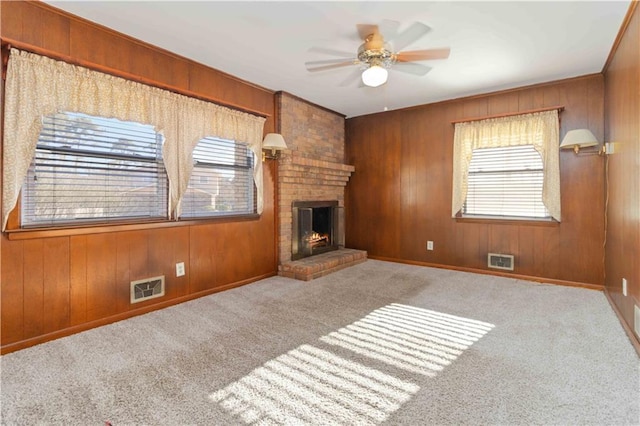 unfurnished living room featuring ceiling fan, light carpet, a fireplace, and wood walls