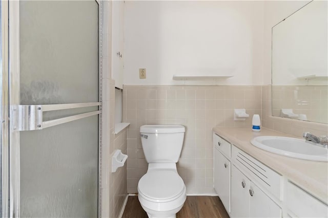 bathroom featuring toilet, hardwood / wood-style floors, tile walls, walk in shower, and vanity