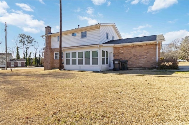 rear view of house featuring a sunroom and a lawn