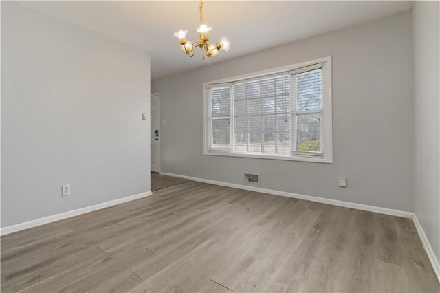 spare room with wood-type flooring and a chandelier