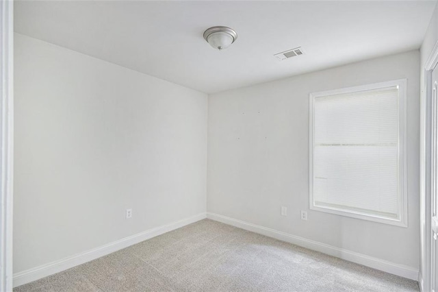 spare room featuring baseboards, visible vents, and light carpet