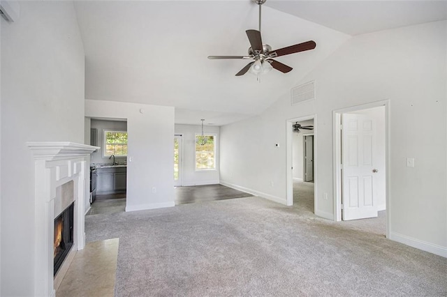 unfurnished living room with ceiling fan, light colored carpet, a sink, and a fireplace