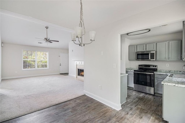 kitchen with dark wood-style flooring, baseboards, open floor plan, gray cabinets, and stainless steel appliances