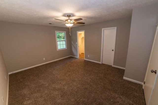 empty room featuring ceiling fan, dark carpet, and a textured ceiling