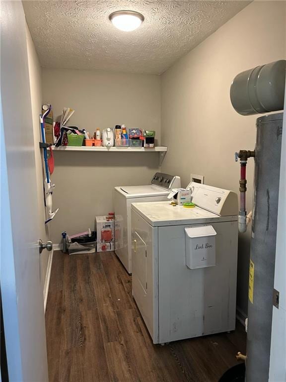 clothes washing area with dark hardwood / wood-style flooring, washing machine and dryer, a textured ceiling, and gas water heater