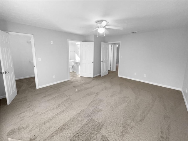 unfurnished bedroom with visible vents, baseboards, ceiling fan, a walk in closet, and carpet flooring