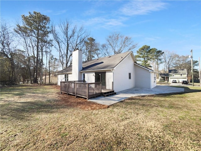 back of house with a chimney, a lawn, a patio area, and a wooden deck