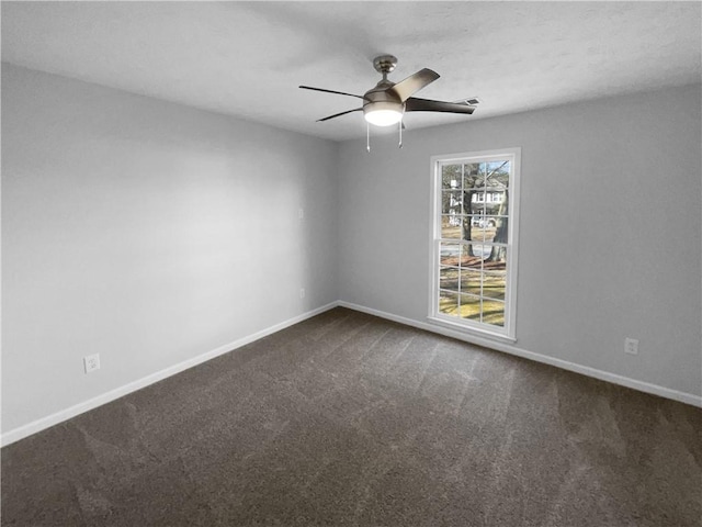 unfurnished room with dark colored carpet, ceiling fan, and baseboards