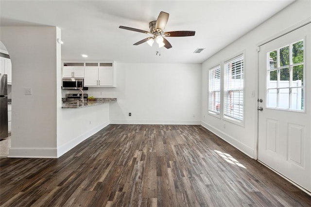 215 Morris Ln, Woodstock, GA 30188 - unfurnished living room with plenty of natural light, dark wood-style flooring, arched walkways, and baseboards
