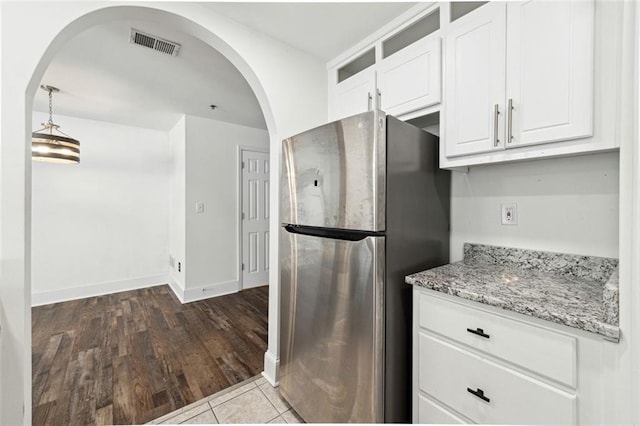 215 Morris Ln, Woodstock, GA 30188 - kitchen with freestanding refrigerator, white cabinets, light stone countertops, arched walkways, and wood finished floors