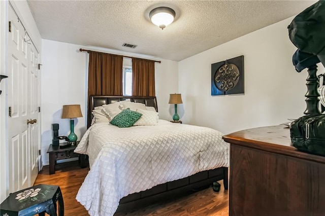 bedroom featuring a closet, dark wood-type flooring, and a textured ceiling