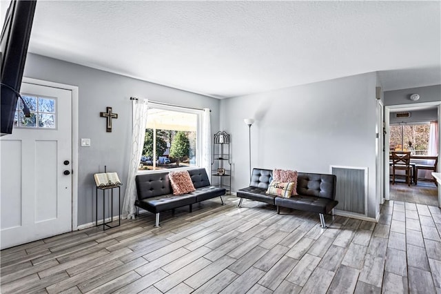 living room with a wealth of natural light, light wood-style flooring, and a textured ceiling