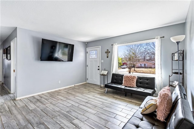 living area with light wood-type flooring and baseboards