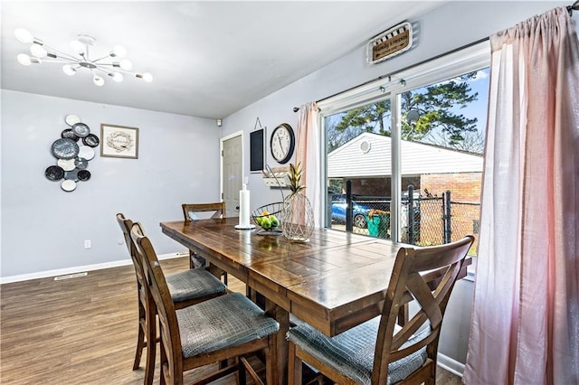 dining room with dark wood-style floors, an inviting chandelier, and baseboards