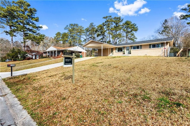 ranch-style house featuring a front yard, a carport, and concrete driveway