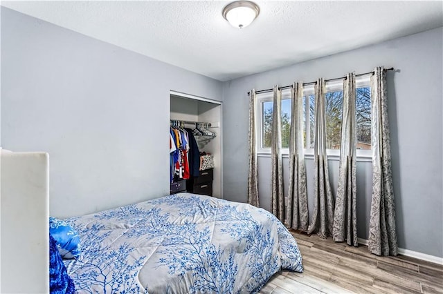 bedroom with a textured ceiling, a closet, baseboards, and wood finished floors