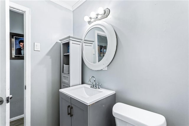 half bath featuring ornamental molding, vanity, and toilet