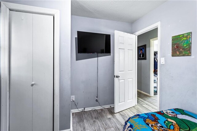 bedroom with light wood-style floors, baseboards, and a textured ceiling