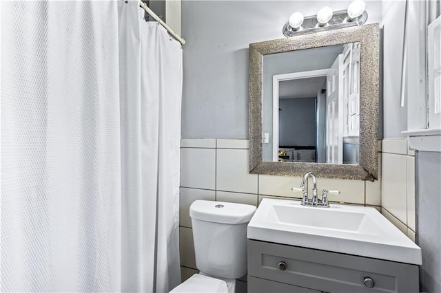 bathroom featuring tile walls, vanity, and toilet