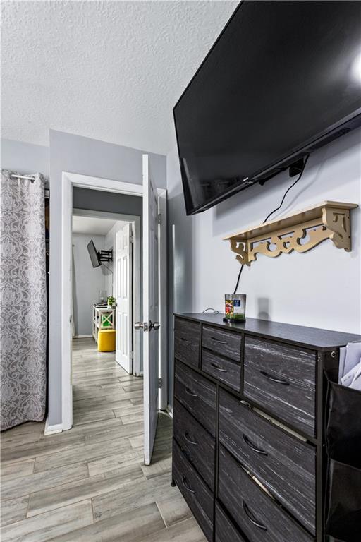 interior space featuring light wood-type flooring, a textured ceiling, and baseboards