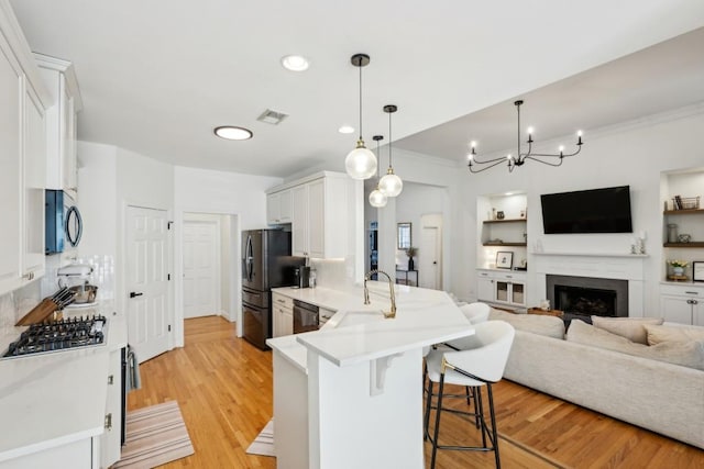 kitchen with black appliances, white cabinetry, a kitchen breakfast bar, sink, and kitchen peninsula