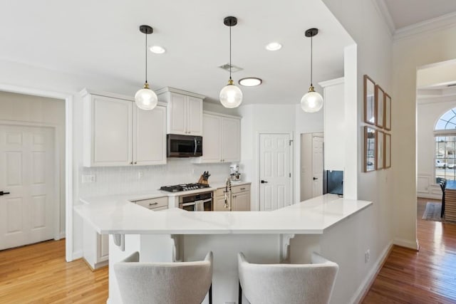 kitchen featuring kitchen peninsula, white cabinets, a breakfast bar, and appliances with stainless steel finishes