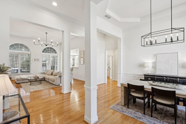 dining space featuring hardwood / wood-style flooring, a notable chandelier, crown molding, and ornate columns